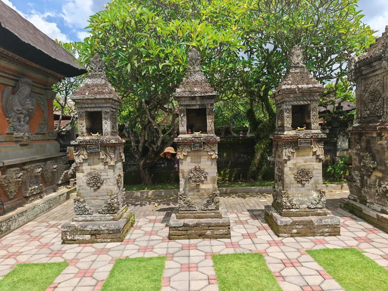 Carved stone shrines in a sunlit Balinese courtyard
