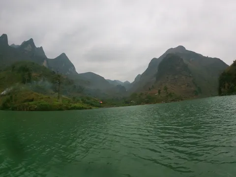 Green river water beneath misty, steep mountains